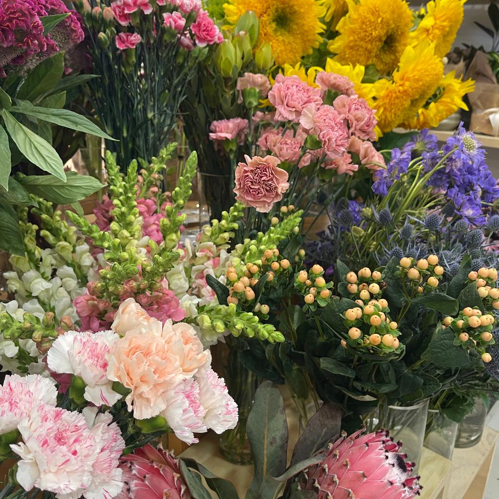 Assorted flowers including pink, yellow, and green bouquets on a table.